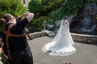 A candid moment of Megan Photographing a bride at the Inn and Laurel Point Hotel, with a waterfall behind her.