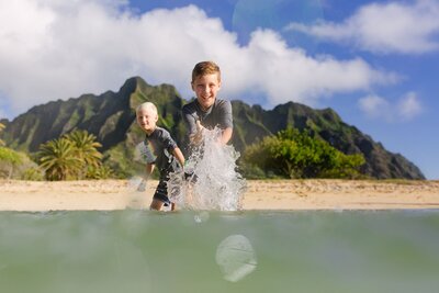 Two kids splash with water in the ocean.