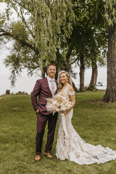 Bride and Groom in Fon du Lac Wisconsin . Bride looking at the camera holding her bouquet under a tree at their private estate wedding.