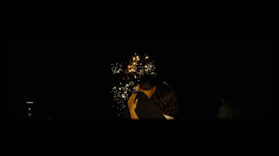 The bride and groom embrace, gazing at the wedding fireworks. Capturing love and enchantment in the night sky