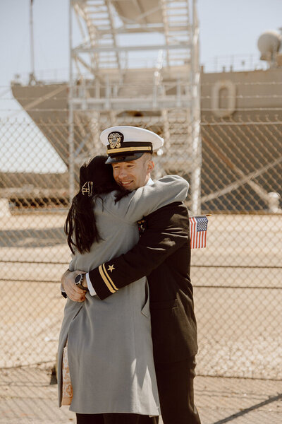 After a long deployment, Navy sailor returns back to Norfolk, Virginia and embraces his wife in a hug for a sweet military homecoming moment. 
