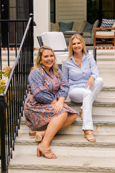 real estate agents wearing coordinate outfits sitting on patio stairs during brand photoshoot with Laure Photography