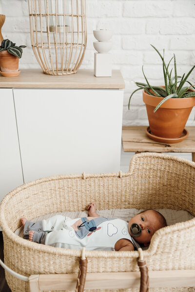 Baby wearing a cozy outfit, sitting in a well lit room playing with a wooden baby toy. 