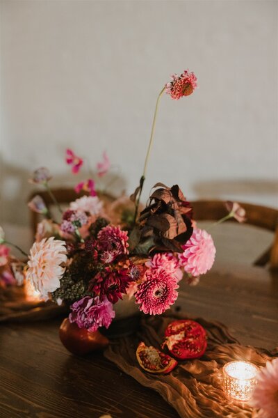 Bright pink and red florals with a glowing candle designed by New Jersey Floral Designer, Jessamine Floral & Events