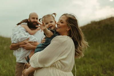 mother and father holding children in field