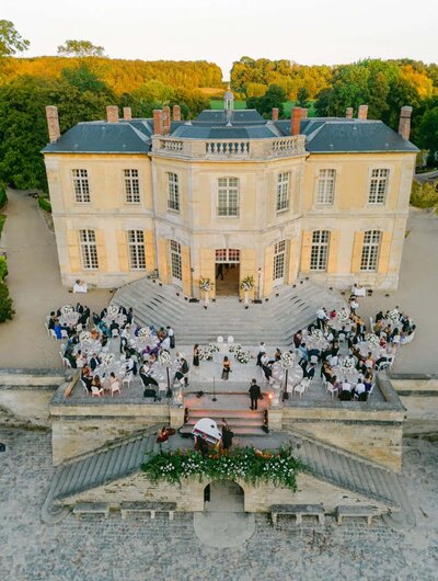 Luxury destination wedding reception at a French château with guests dining outdoors, photographed by Thomas Raboteur, destination wedding photographer