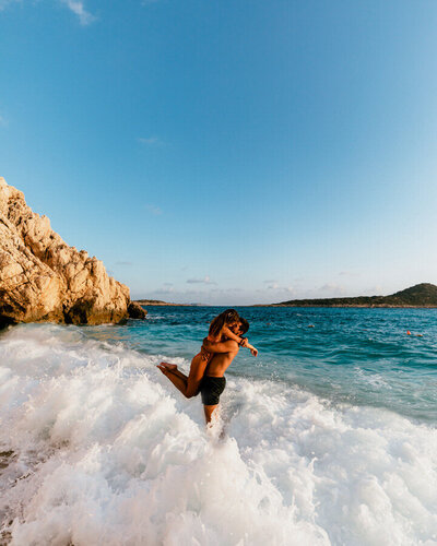 man and woman kissing in crashing waves