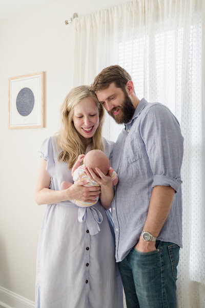 New parents hold their baby during a luxury newborn photoshoot at home.