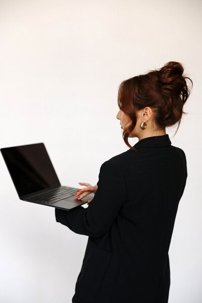 A monochromatic image of the founder of House of Virtua Mind in a white suit, poised at a laptop