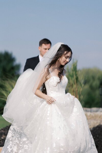 Bride walking with groom holding the train of the dress at Mohawk River Country Club
