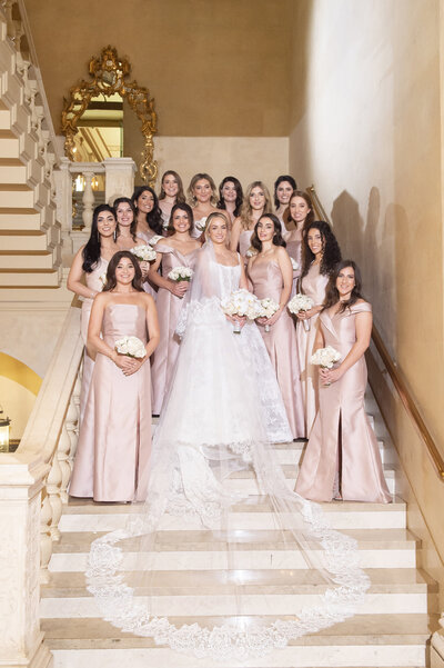 Bride with bridesmaids in pink dresses standing on stairs