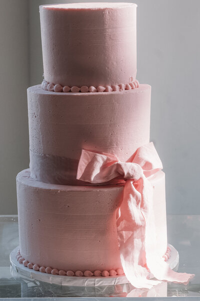 detail shot of a three tier pink wedding cake with pink bow, taken at Red berry estate wedding by luxury wedding photographer ShyLaurel Photograohy