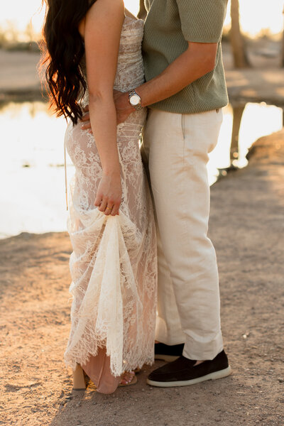 half body cropped photo of a couple embracing in front of the papago park lake