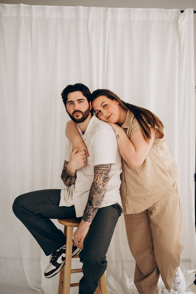 A person sitting on a chair as their partner leans on their back