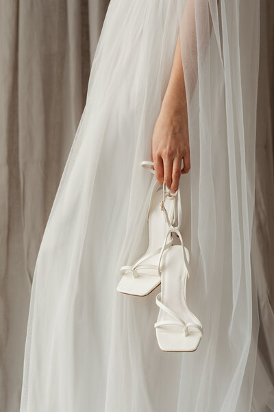 Bride holding white wedding heels