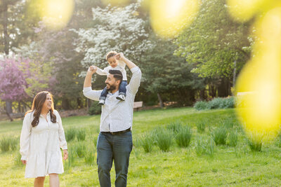 Mom and dad in nature with their child on dad's shoulders