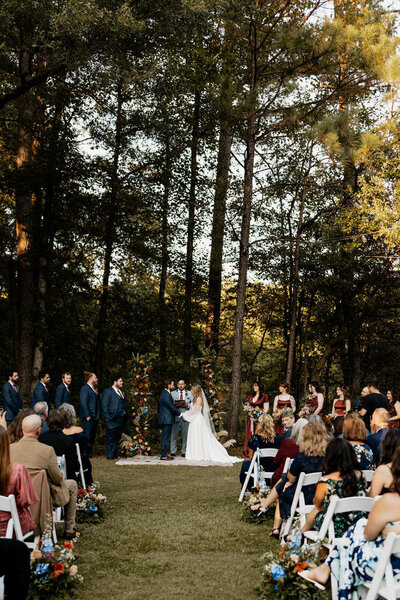 A romantic, documentary-style photograph capturing a bride and groom sharing a tender moment at Daniel Stowe Botanical Garden. This elegant wedding photography session highlights the couple's love amidst the lush, vibrant greenery of this beautiful venue.