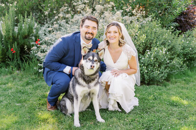 a bride and groom pose for a photo with their dog at their brazilian room wedding.