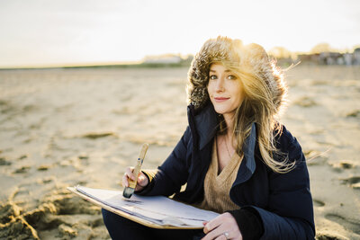 woman sketches on a beach in winter