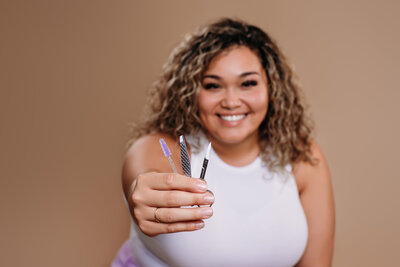 Brand photo of a smiling wax specialist holding up her tools by Alyssa Daken