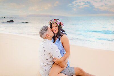 Couple in love and kissing on the beach  during their babymoon portraits with Love + Water