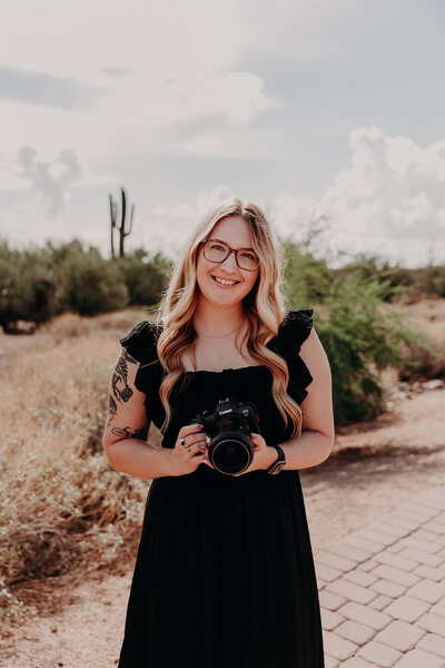 Suzy goodrick poses with her camera in the phoenix desert
