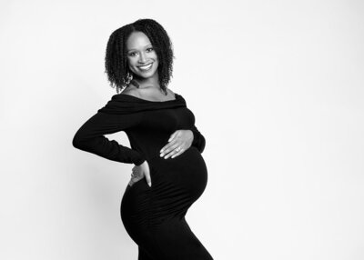 black and white portrait of beautiful pregnant black woman in black dress with her hand on her belly