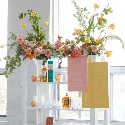 A lush and colourful flower arrangement sits on top of the bar at a L'Eloi wedding reception. 