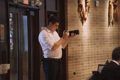 Jacob Metzger, a freelance wedding videographer, holding a camera at a wedding.