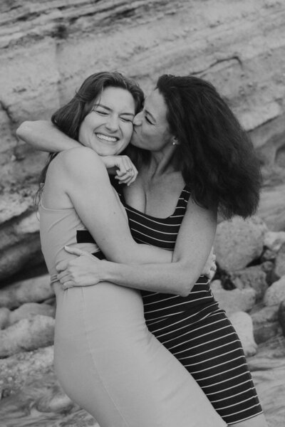 two women kissing and hugging in black and white