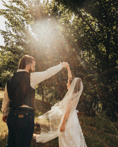 Bride and groom dancing in front of a tree and beautiful sunlight after ceremony 