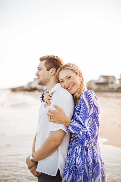 Engaged couple embracing on the beach at sunset during their Portland Maine engagement session.