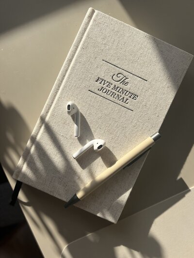 A woman wearing a beige knit sweater, black trousers, and a black suede tote bag walks down a tree-lined New York City street on a rainy day, showcasing a chic and casual urban outfit.