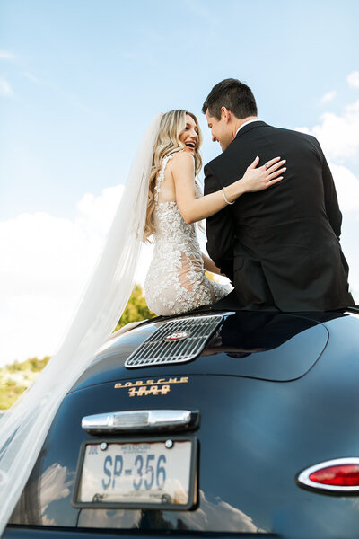 bride and groom smiling on getaway car
