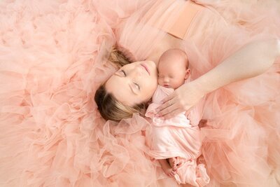 Charlotte mom cradles her peaceful newborn baby girl, swaddled in pink. Captured by Alicia Insley Smith Newborn Photography Charlotte NC