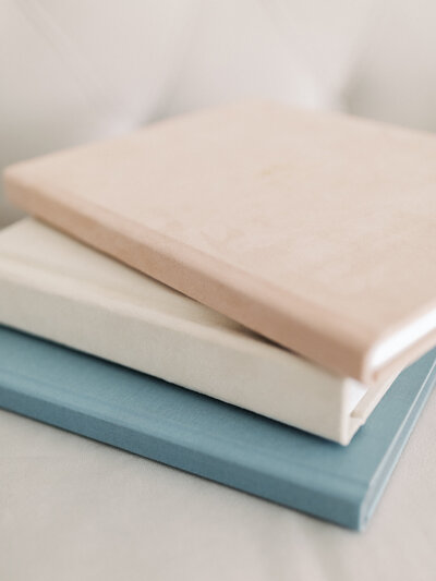 A photo of three pastel coloured photo albums stacked on top of each other.