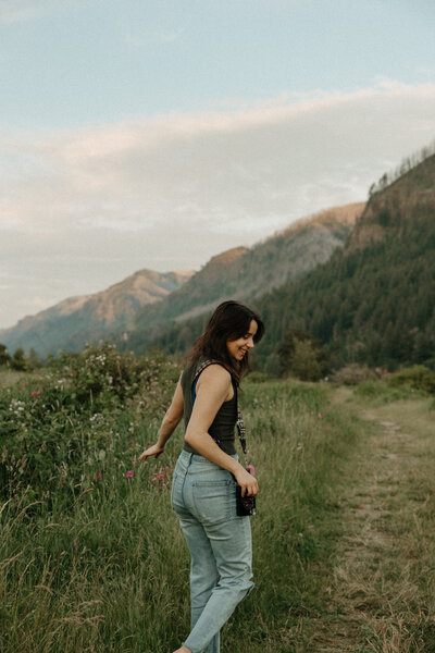 Destination wedding photographer poses in front of PNW greenery