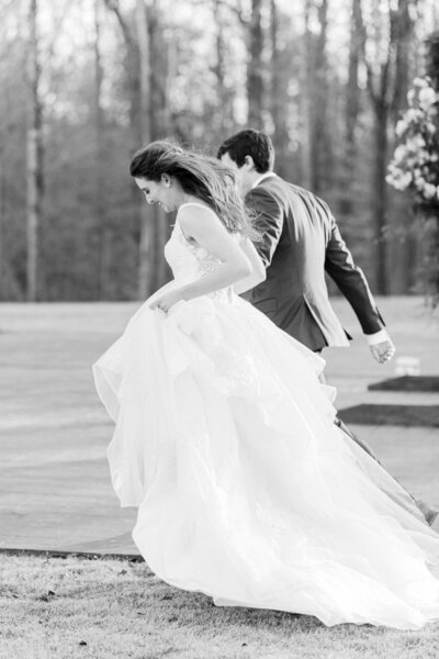 bride and groom running in fiel