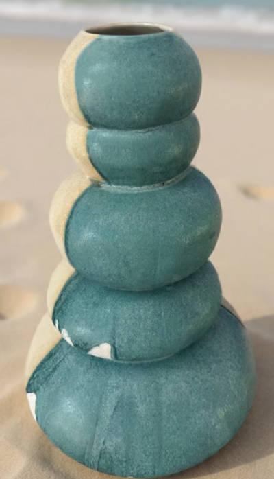 Jill stands beside her teal vase with relief detailing inside of The Studios of Key West