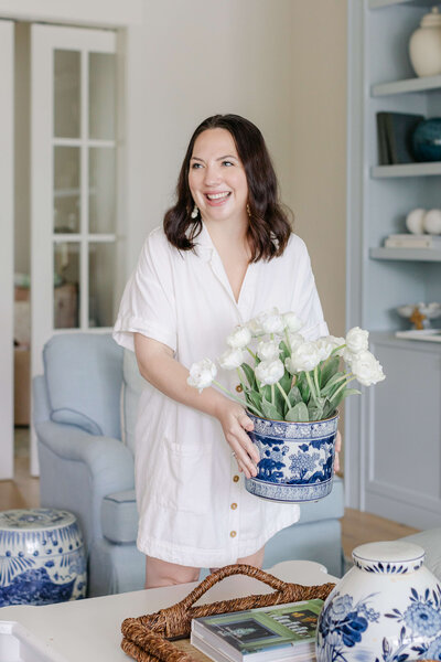 lola interiors team team member holding a blue vase with white flowers