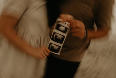 a couple holding ultrasound  images of early pregnancy
