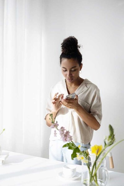 Young woman with updo taking picture of floral arrangement