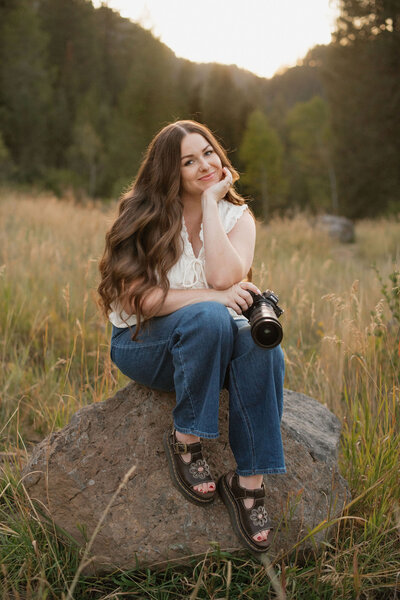 Branding photo for Bailee Freeman Photography with a black blazer and a Nikon camera in front of her. 