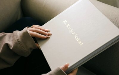 A white canvas wedding album with flat lay photos of the bride and groom's wedding day.