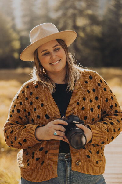 Yosemite elopement photographer McKayla Sullivan holds a camera and smiles