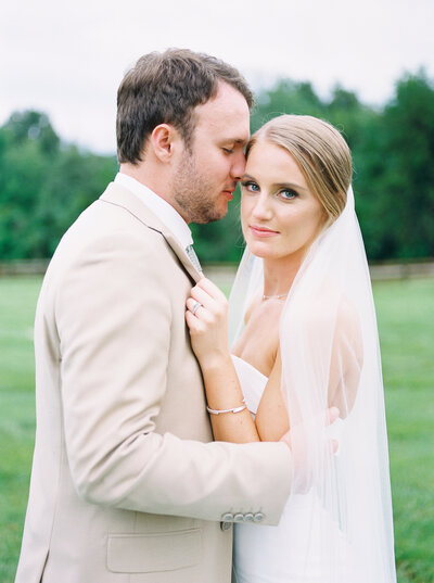 Groom embracing the bride while bride looks at the camera