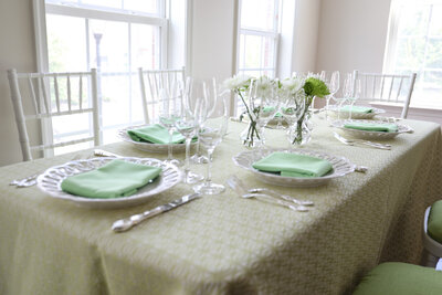 Dining table designed with floral centerpiece,  plates, utensils, glasses and green table napkin