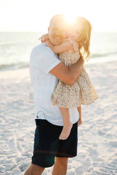 Dad and daughter embrace with a sun-kissed beach session in Argyle, Texas.