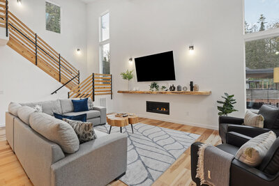 Living room with a fireplace, mounted TV, and gray sofas