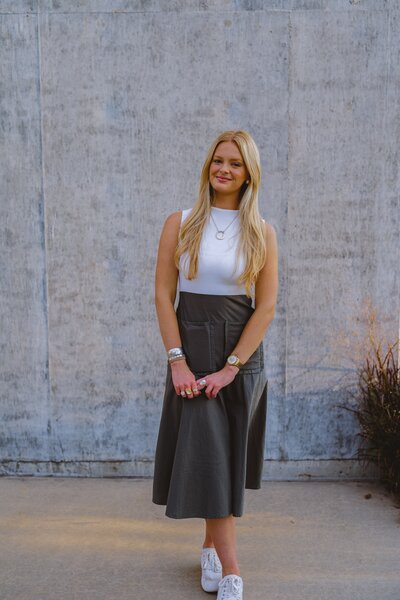 Woman in white dress in front of teal building